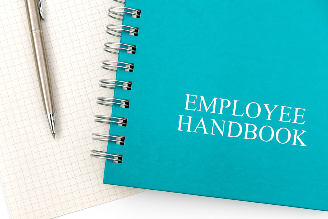 Employee Handbook or manual with a pen and paper on a white table in an office.